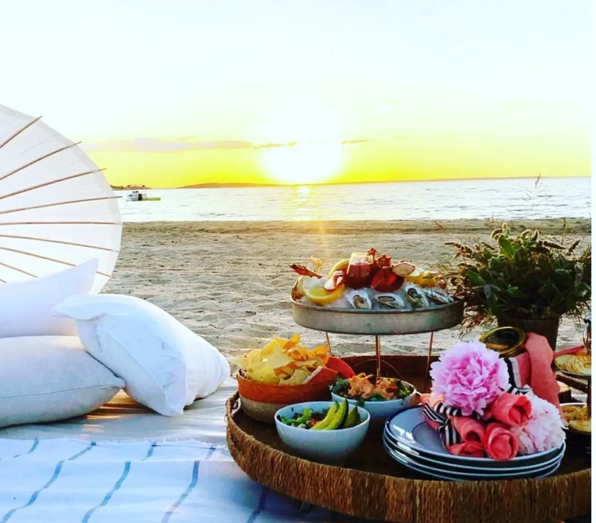 Beach picnic with flowers and food at sunset